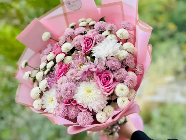 A pink and white flower bouquet wrapped in pink paper