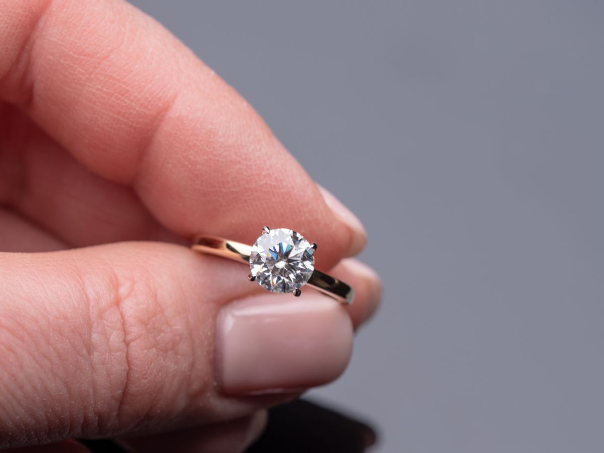 Hand holding a diamond ring with rose gold band