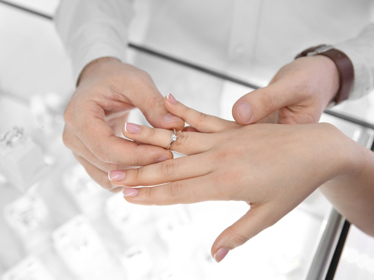Man placing engagement ring on woman's finger