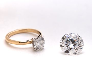 Gold ring with large diamond setting, next to a loose round brilliant diamond.