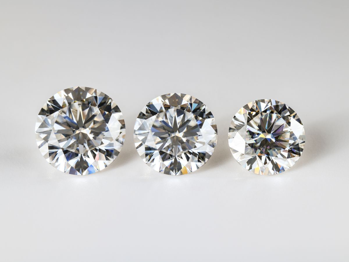 Three round brilliant cut diamonds, aligned in a row on a white surface.