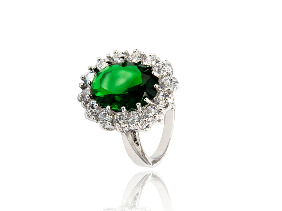 Emerald ring with diamond halo on white background