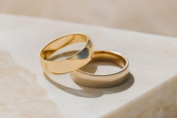 Pair of classic gold wedding bands on marble surface