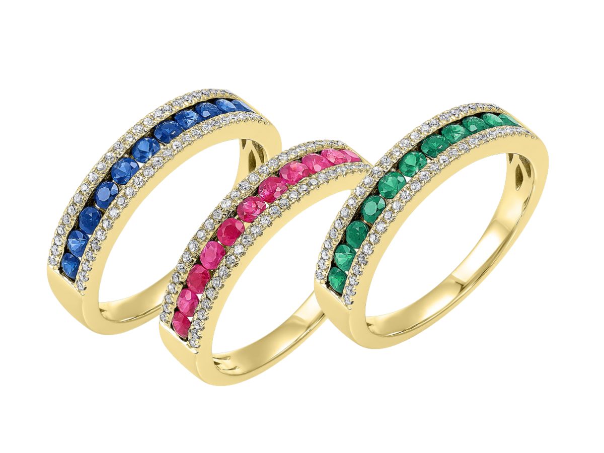 Three yellow gold wedding bands with sapphire, ruby, and emerald gemstones set in pavé diamond accents