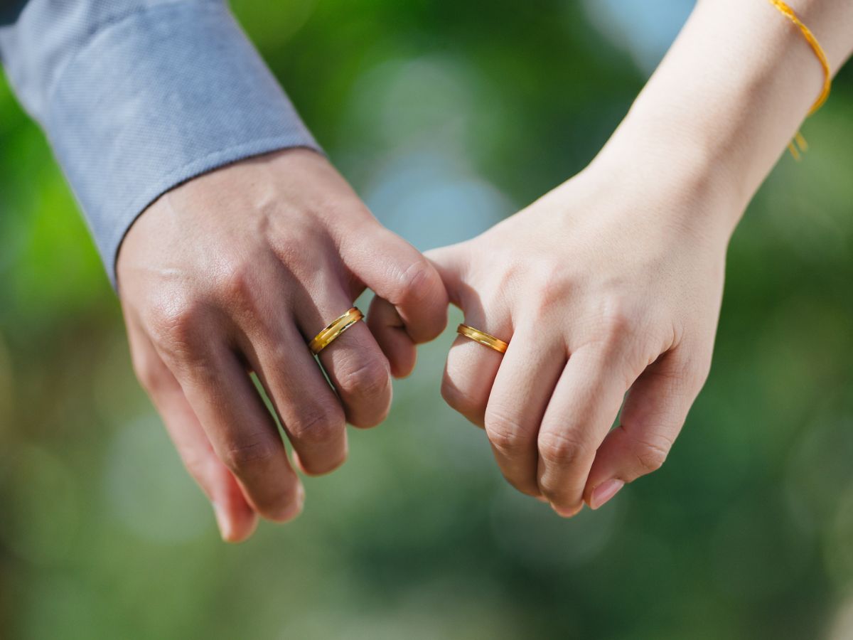 Couple holding hands wearing matching gold wedding bands