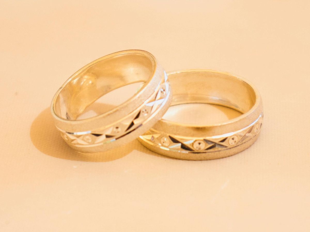 Two gold wedding bands with intricate patterns on display.