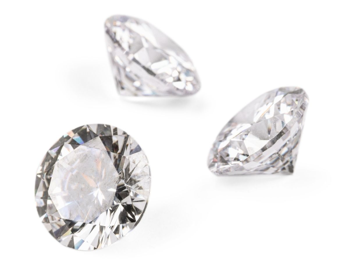 Three round brilliant-cut diamonds on white background sparkle brightly