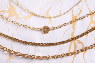 Assorted gold chains on marble patterned surface