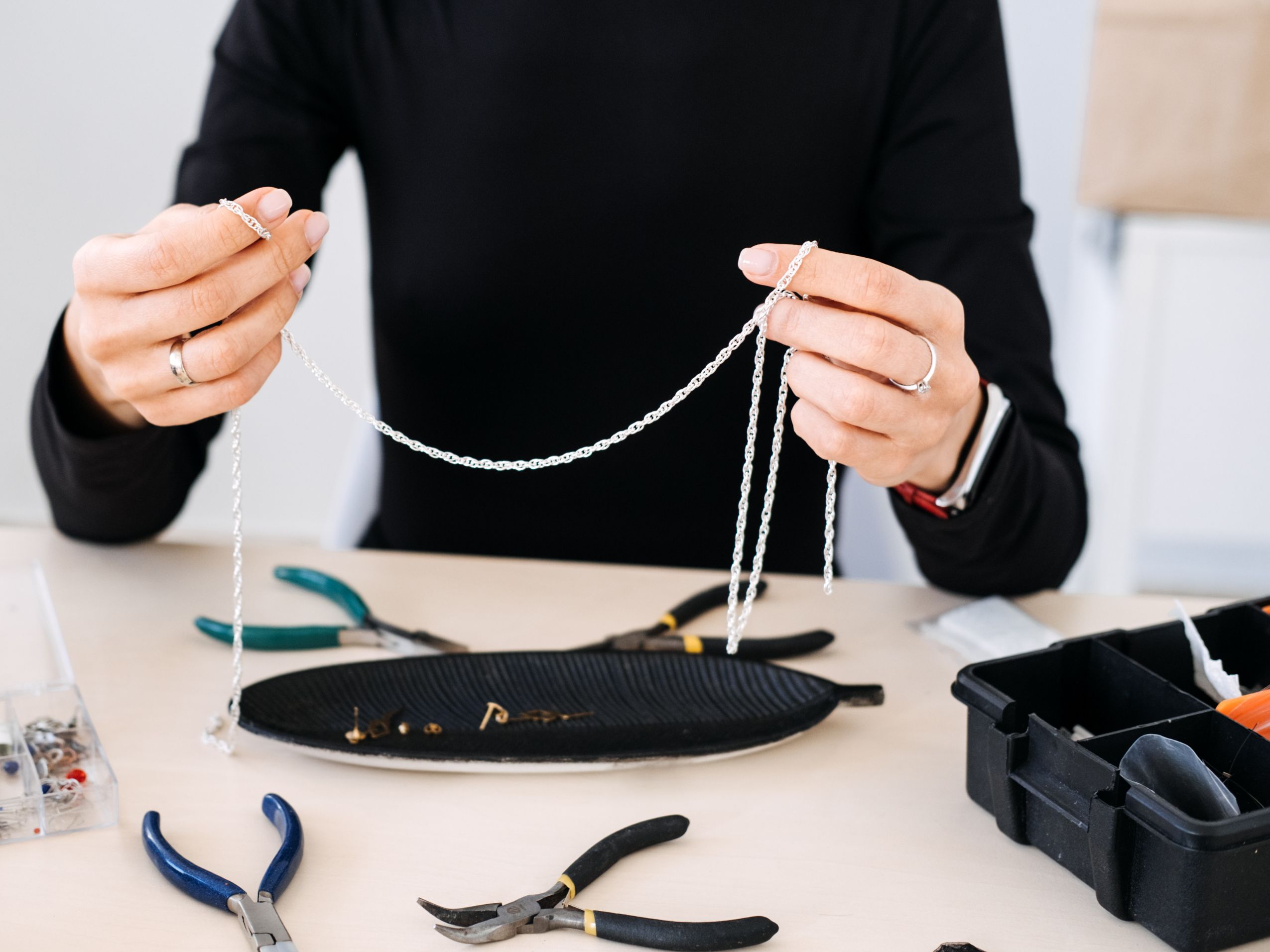 Jewelry artisan holding silver chains at work table