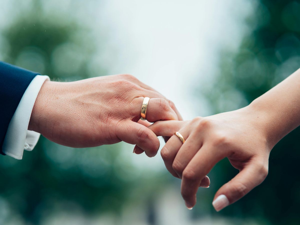 Close-up of couple's hands placing wedding bands on each other’s fingers
