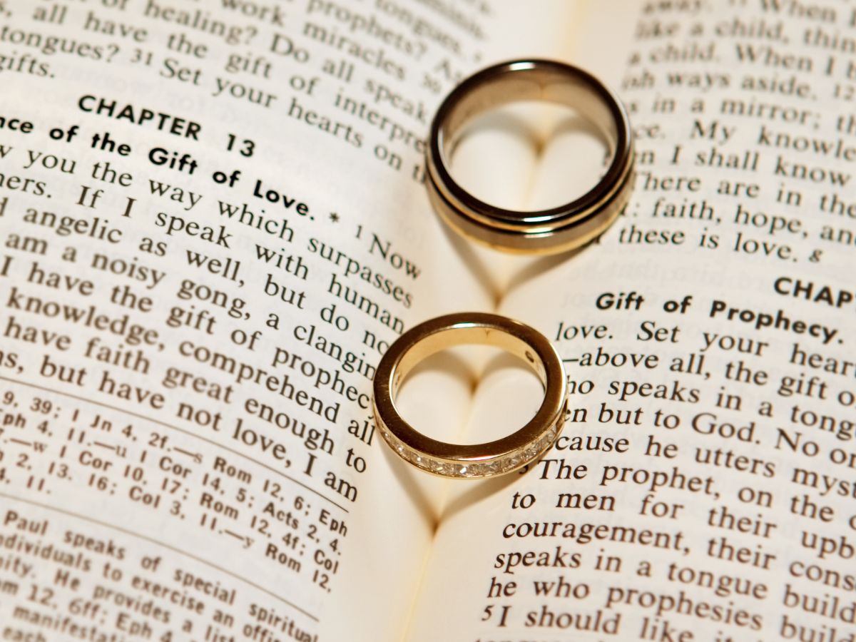 Two wedding rings rest atop a Bible, symbolizing love and faith.