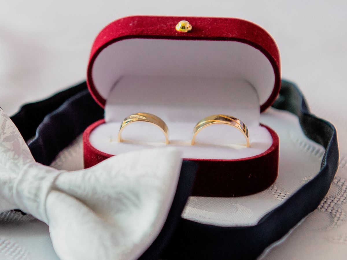 Gold wedding bands in red velvet box with bow tie
