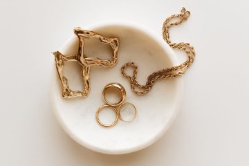 Gold fine jewelry set on a round white marble display surface.