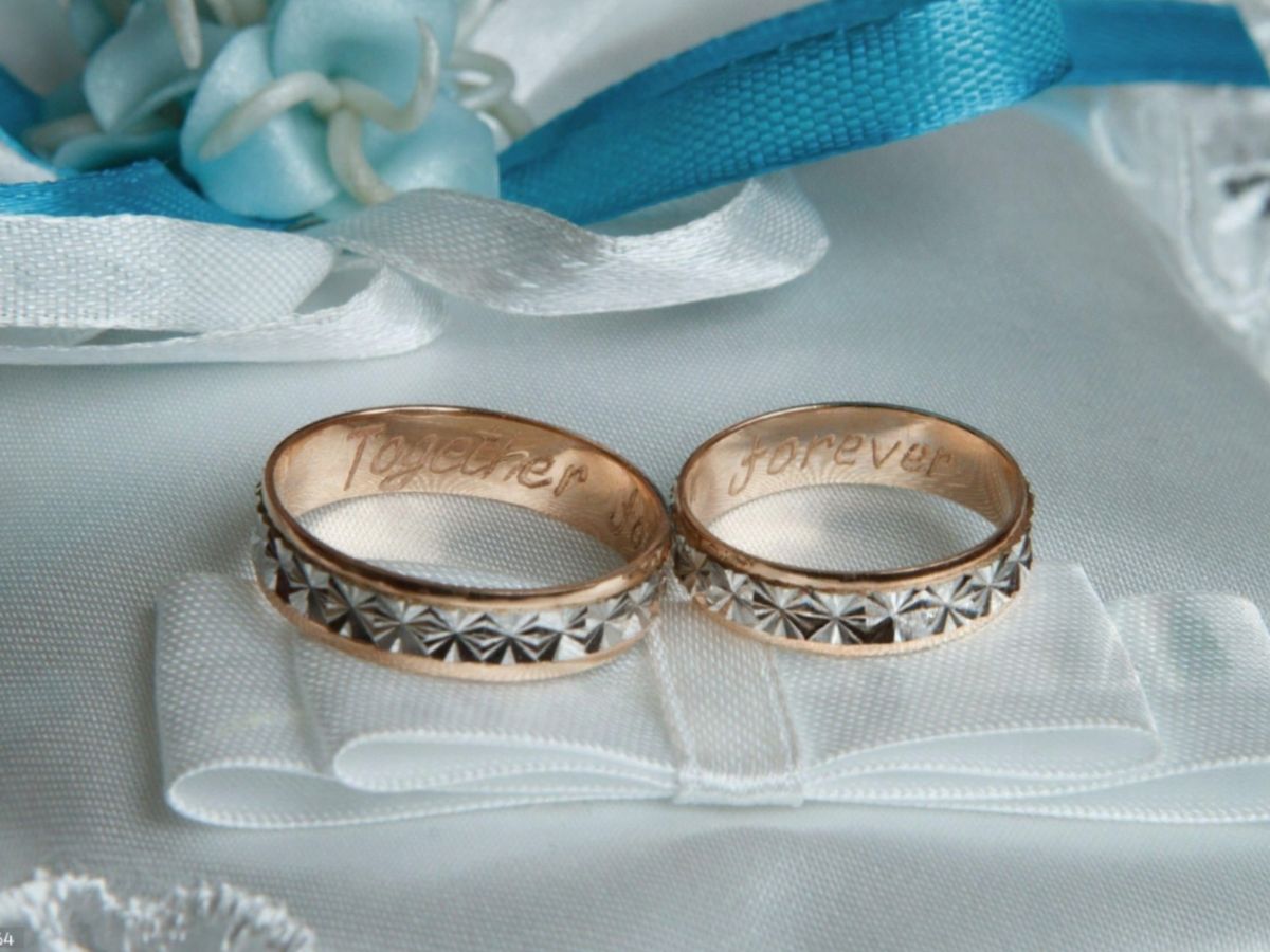 Wedding bands engraved Together Forever on fabric surface