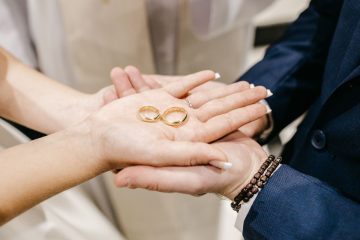 Close-up of couple’s hands holding gold wedding rings