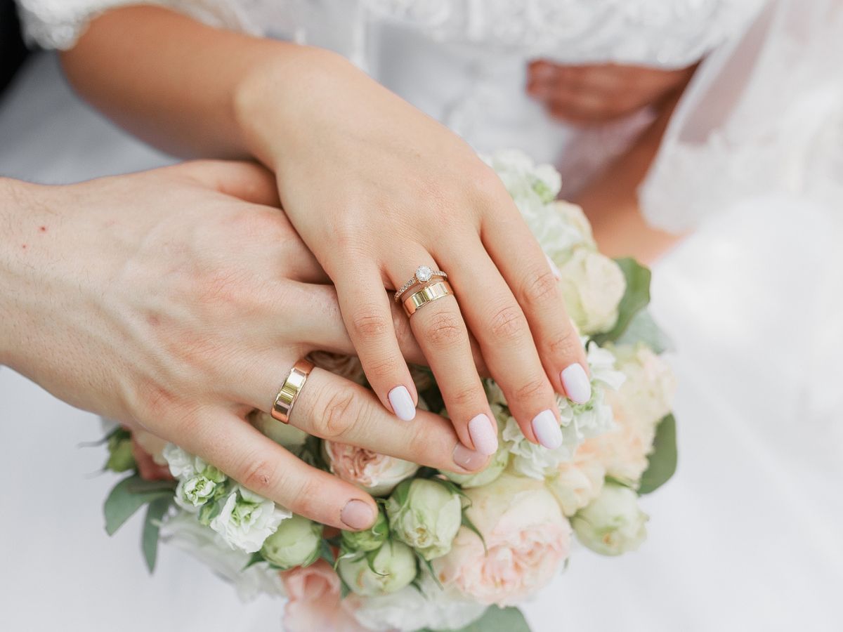 Bride and groom hands with rings and floral bouquet