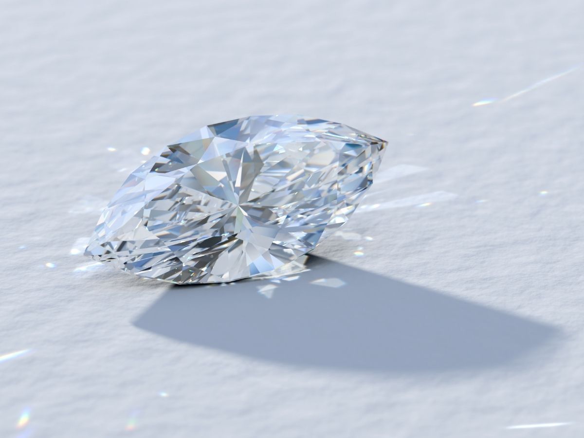 A sparkling marquise-cut diamond on a white surface, showcasing its brilliance and shine.