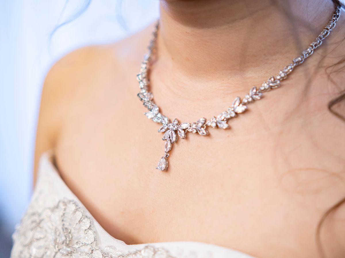 Elegant bride wearing floral diamond necklace with drop pendant detail.