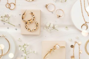 Assorted gold jewelry with pearl accent on pastel display