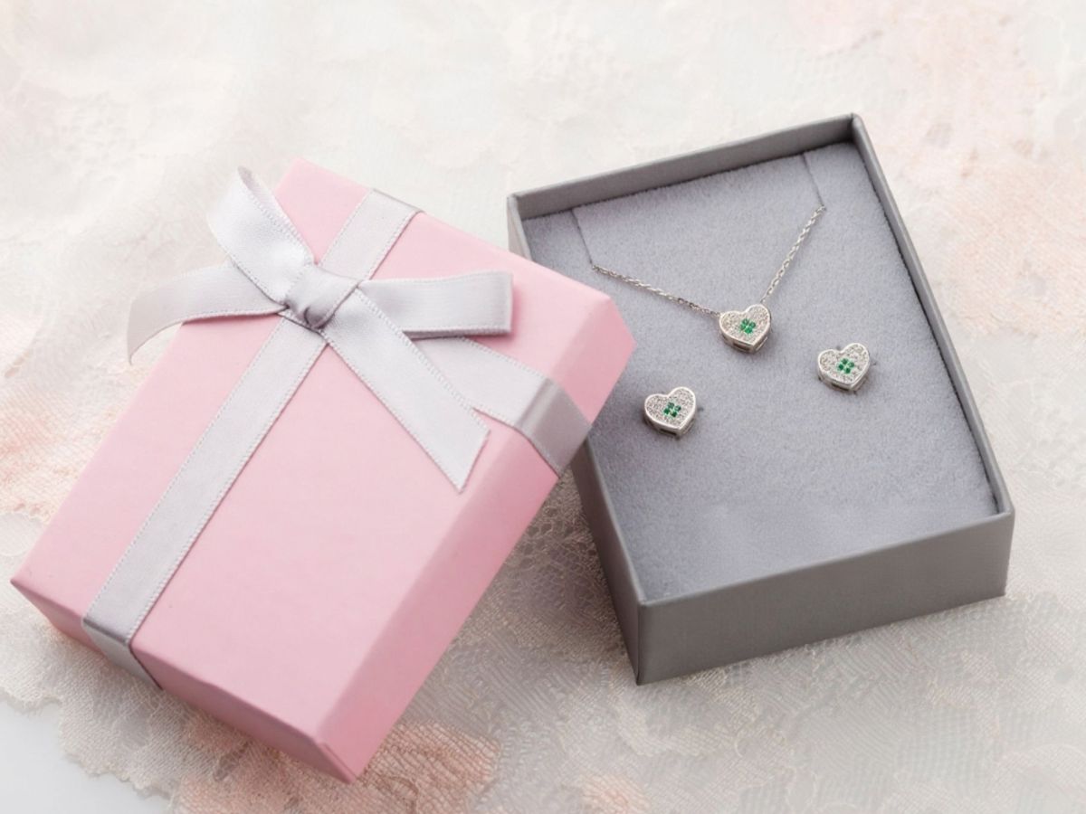 Heart-shaped silver jewelry set with emerald gems in a gift box
