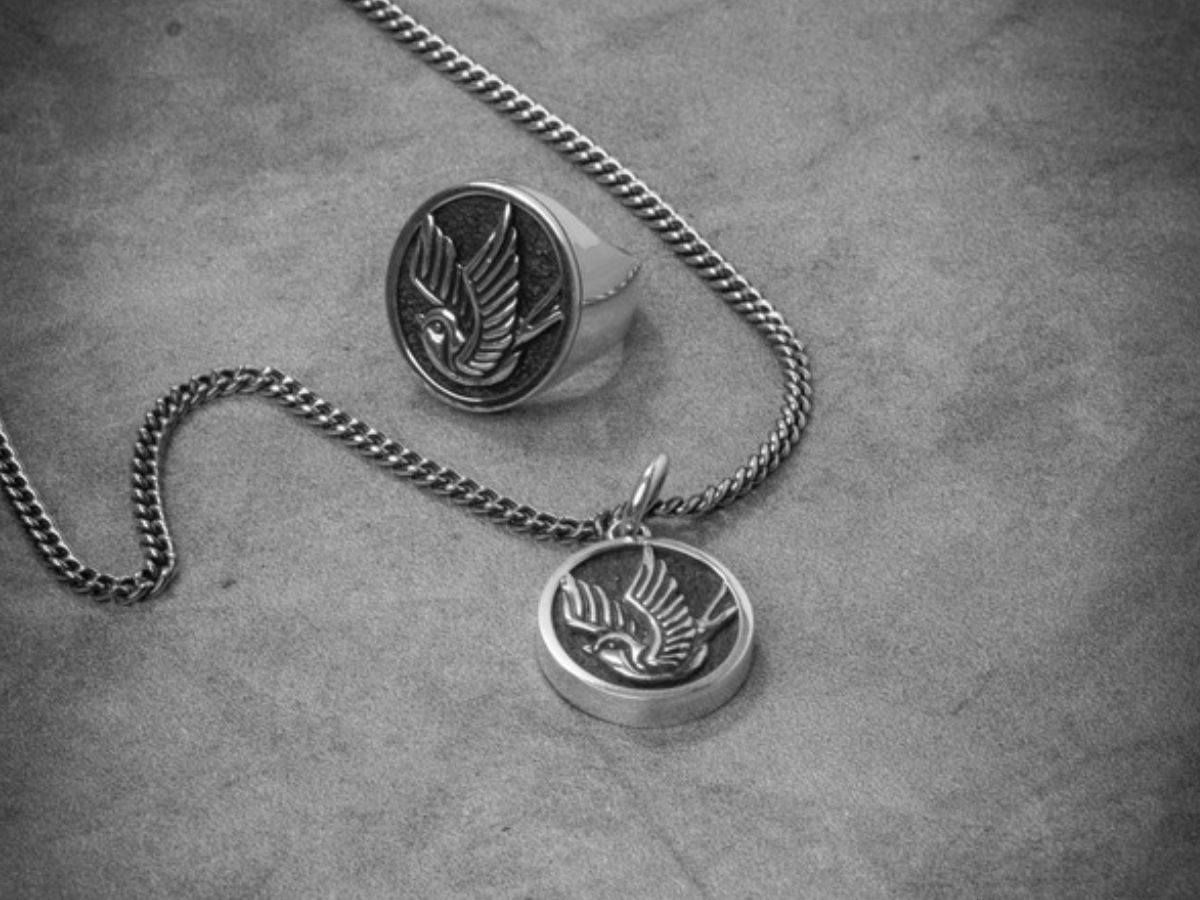 Silver pendant necklace and ring set with engraved bird design on metal