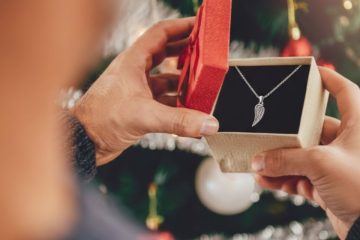 Man opening gift box with silver angel wing pendant