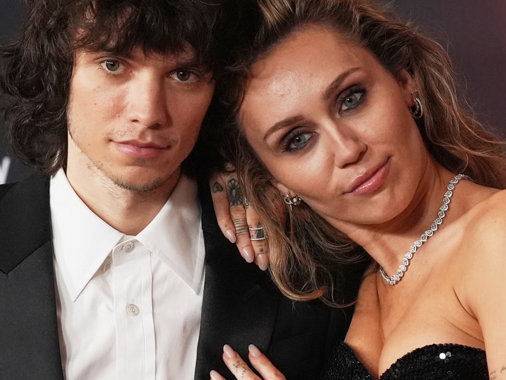 Miley Cyrus gold diamond engagement ring and diamond eternity band while posing at red carpet event.