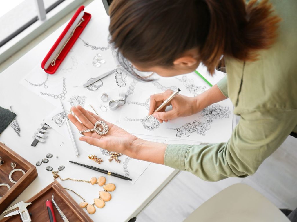 Jewelry designer sketching and arranging pieces.