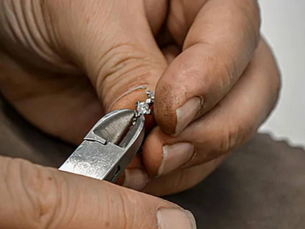 Jeweler tightening diamond prongs with cutting pliers