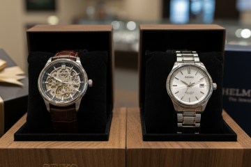 Two Seiko watches, one automatic with a visible movement and one quartz with a clean dial, displayed in open gift boxes with a gift-wrapped box and a HELMUT The Jeweler box in the background.