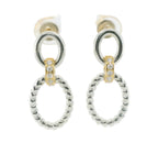 A pair of silver-toned drop earrings with a thick textured oval pendant, a smaller circular ring above it, and a small gold-toned accent section set with clear stones.