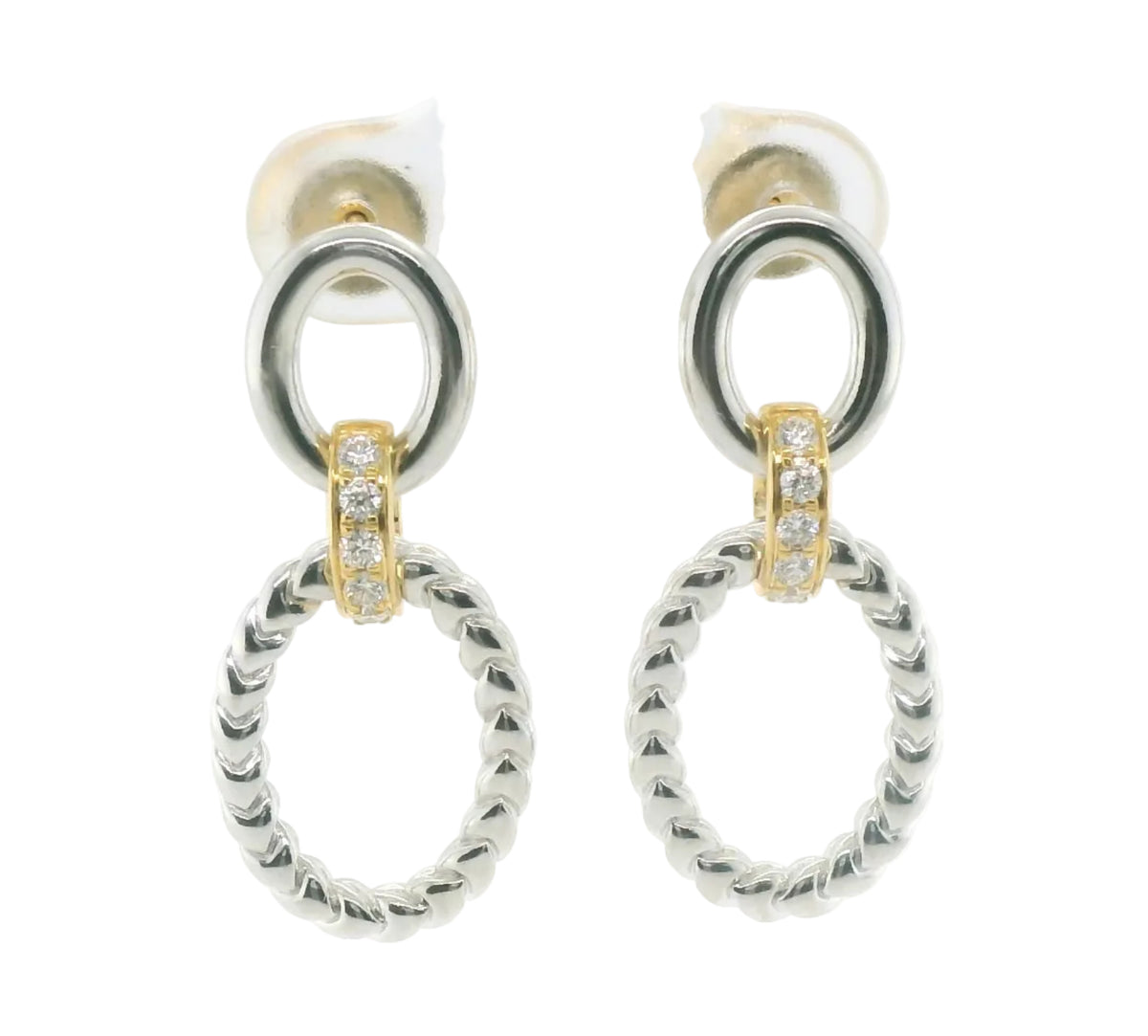 A pair of silver-toned drop earrings with a thick textured oval pendant, a smaller circular ring above it, and a small gold-toned accent section set with clear stones.