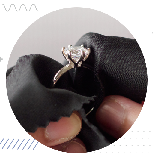 Close-up of a diamond ring being carefully inspected with a soft cloth.