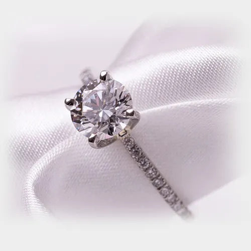 Solitaire diamond ring on white satin ribbon in close-up shot